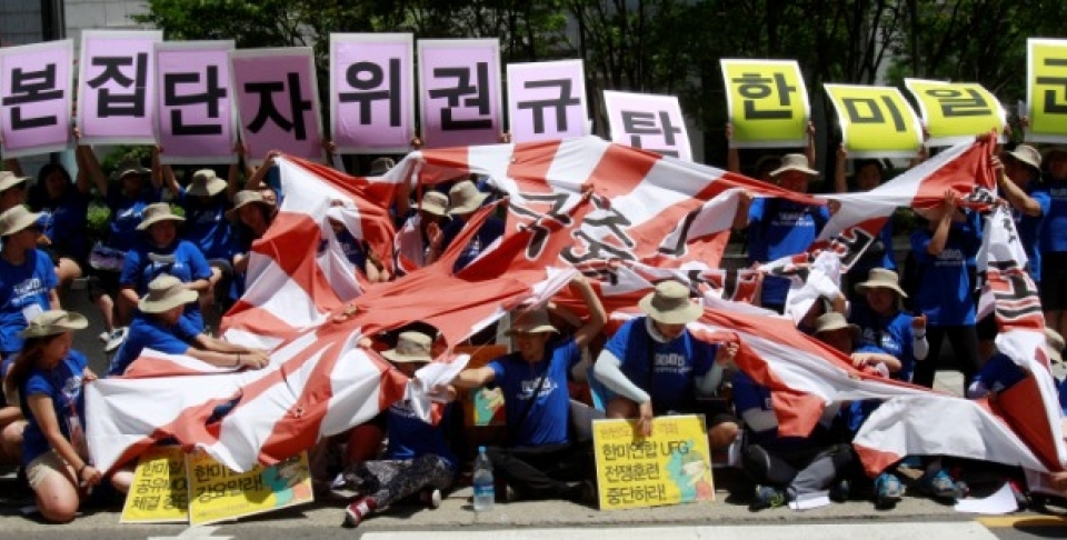 Protesters tear a Japanese rising sun flag during a rally against the Japanese government, demanding not to move toward exercising the right to collective self-defense seen as a prelude to the revival of Japan's past militarism, near the Japanese Embassy in Seoul, South Korea, Friday, Aug. 8, 2014. The cards read "Oppose collective self-defense plan." (AP Photo/Ahn Young-joon)