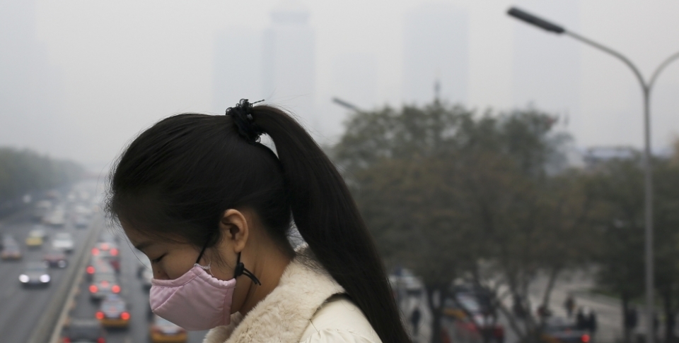 A woman wears a mask to protect herself from pollutants on a hazy day in Beijing. At the G20, the U.S. and China jointly confirmed the ratification of the Paris Agreement. (AP Photo/Andy Wong)