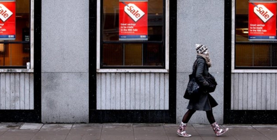 A woman passes a bank advertising a sale on its products, behind Oxford Street in London. (AP Photo/Kirsty Wigglesworth)