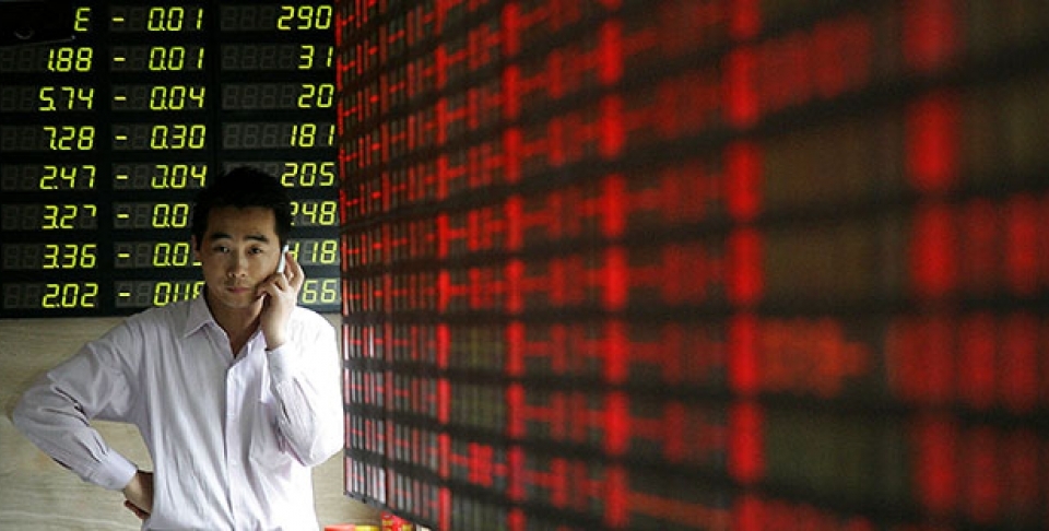 An investor talks on his mobile phone in front of the stock price monitor at a private securities company in Shanghai, China. (AP Photo)