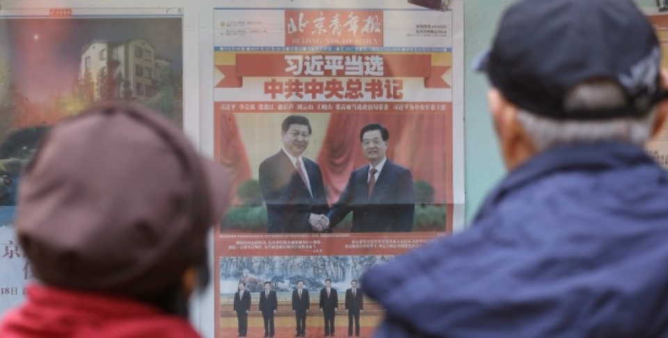 A Chinese couple look at a newspaper carrying photos of new General Secretary of the Communist Party of China Xi Jinping, top left, shaking hands with his predecessor Hu Jintao, top right, and Xi and other members of the party leadership in Beijing, China (AP Photo/Lee Jin-man).