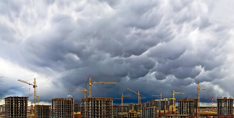 Construction cranes appear along a stormy skyline. (Shutterstock)