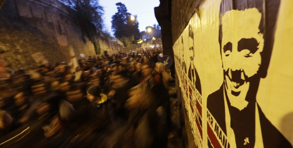 Protesters pass a poster of Italian Premier Matteo Renzi in Rome (AP Photo/Andrew Medichini)