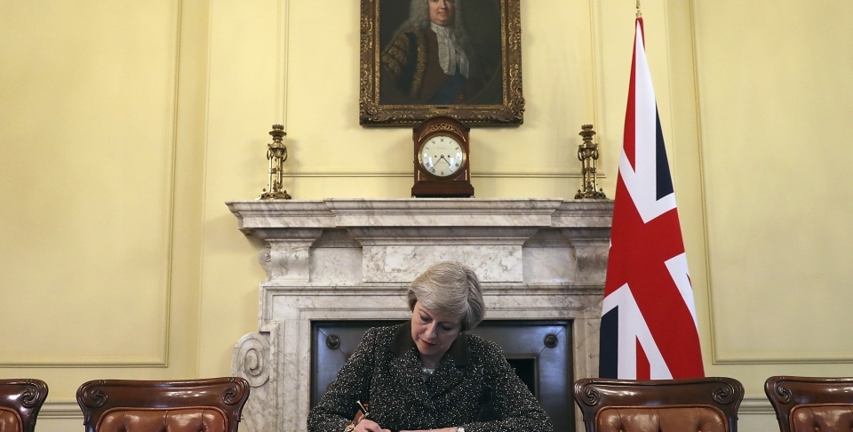 Britain's Prime Minister Theresa May, sitting below a painting of Britain's first Prime Minister Robert Walpole, signs the official letter to European Council President Donald Tusk, in 10 Downing Street, London, Tuesday March 28, 2017, invoking Article 50 of the bloc's key treaty, the formal start of exit negotiations. (Pool Photo via AP/Christopher Furlong)