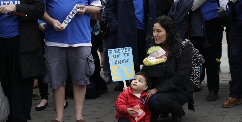 Protesters stand outside the House of Commons in London as Brexit negotiations begin (AP Photo/Matt Dunham)