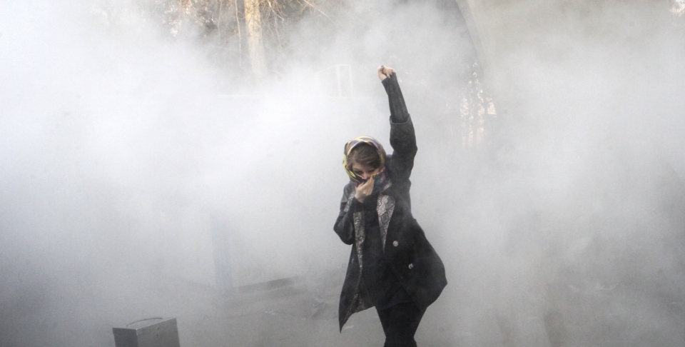 A protestor runs from a smoke grenade thrown by anti riot police during a December 30 rally against the Iranian government. (AP Photo)