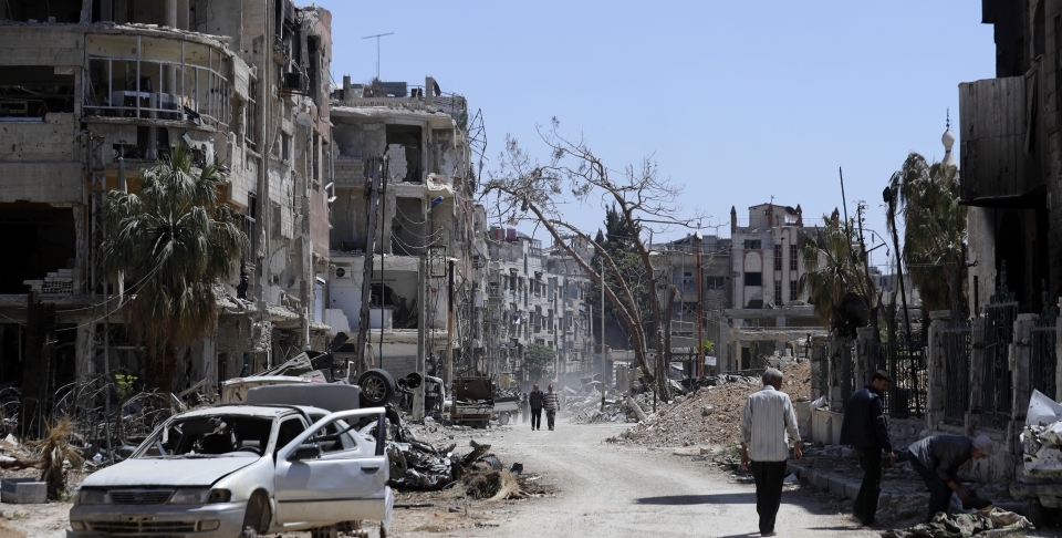 Syrians walk through destruction in the town of Douma, the site of a chemical weapons attack on Monday, April 16, 2018. (AP Photo/Hassan Ammar)