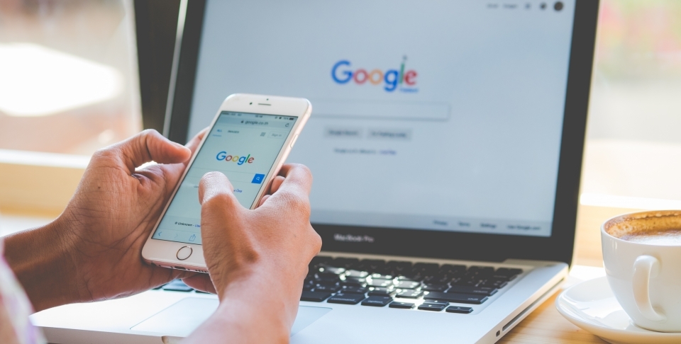 A woman is typing on Google search engine from a laptop and smart phone. (Shutterstock)