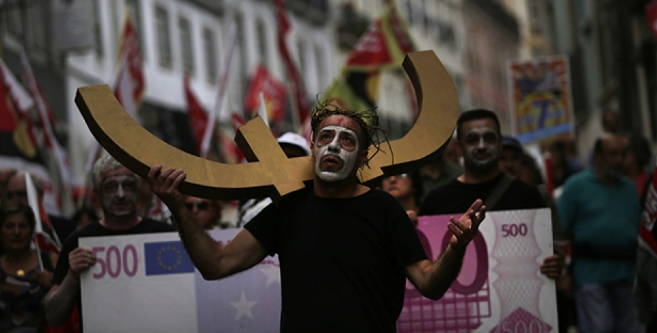 A man carries a euro currency symbol on his shoulder as he marches with others towards the parliament during a protest against austerity measures in Portugal. (AP Photo/Francisco Seco)