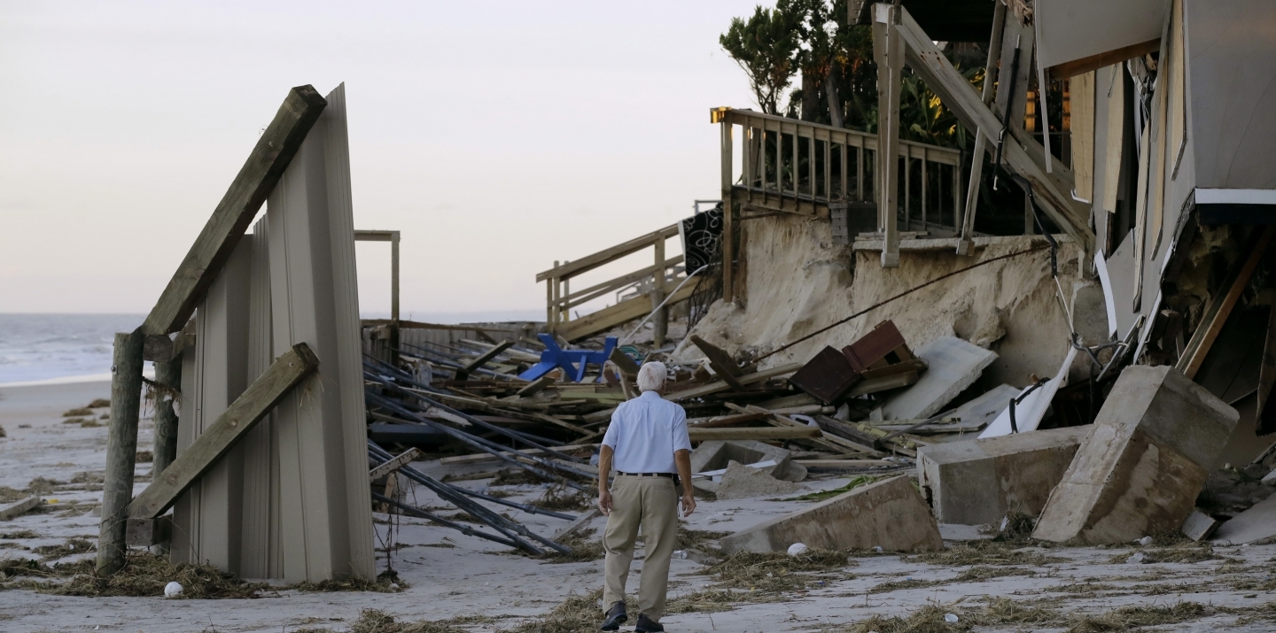 A man looks at damage to a neighbor's home at Ponte Vedra Beach, Fla., Saturday, Oct. 8 , after Hurricane Matthew passed through Friday. (AP Photo/Charlie Riedel)