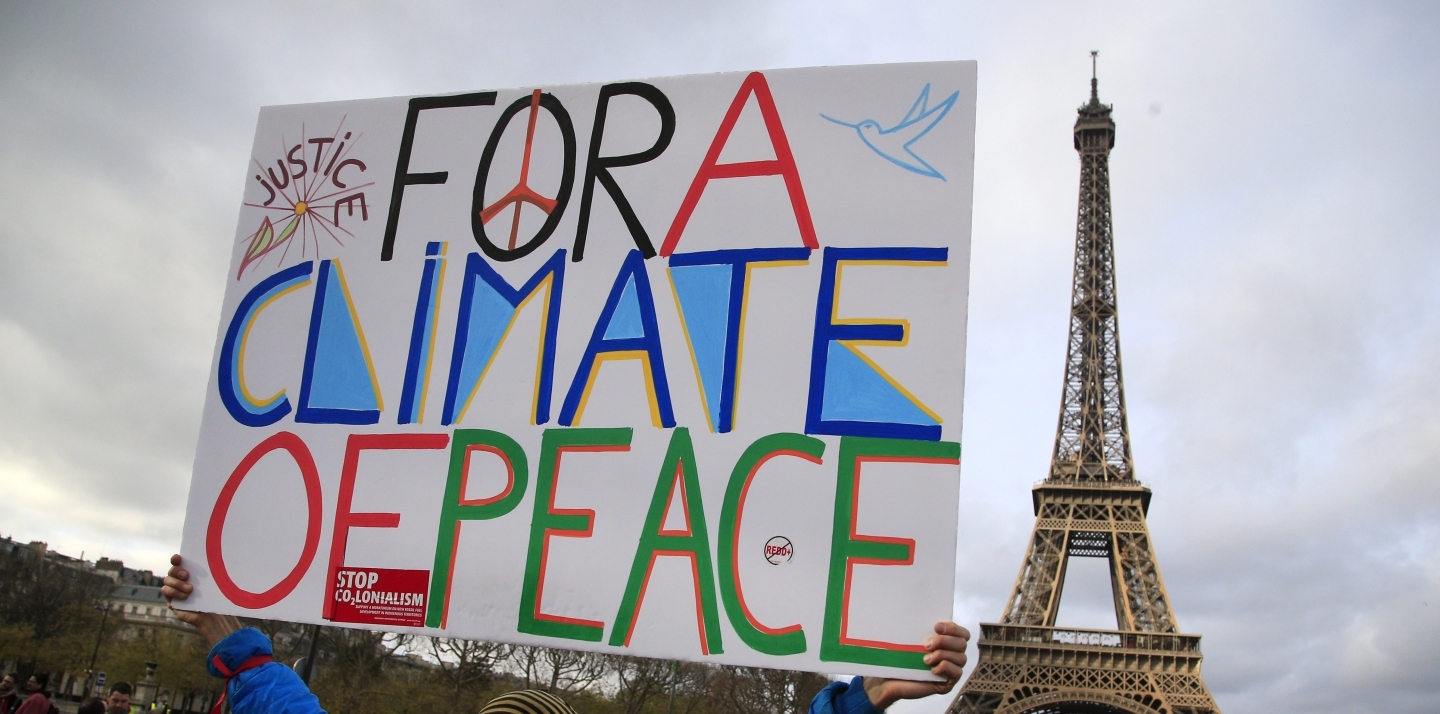 An activist holds a poster during a demonstration in Paris on Dec.12, 2015 during COP21. (AP Photo/Thibault Camus)