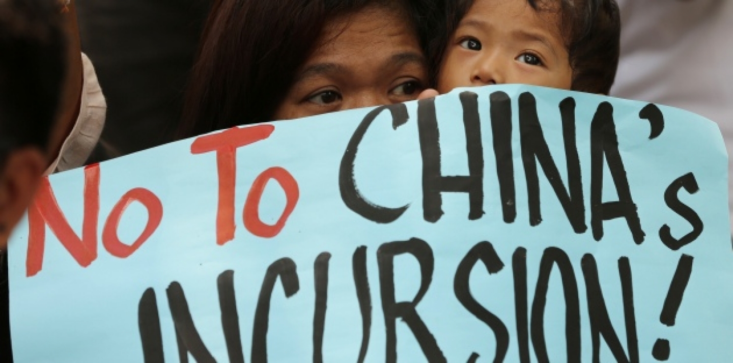 A Filipino protester holds a child as they join a rally outside the Chinese consulate at the financial district of Makati, south of Manila, Philippines on Tuesday, April 22, 2014. The group is demanding an end to China's alleged incursions in the South China Sea and to press the Chinese government to respect the arbitral process under the UNCLS. (AP Photo/Aaron Favila)