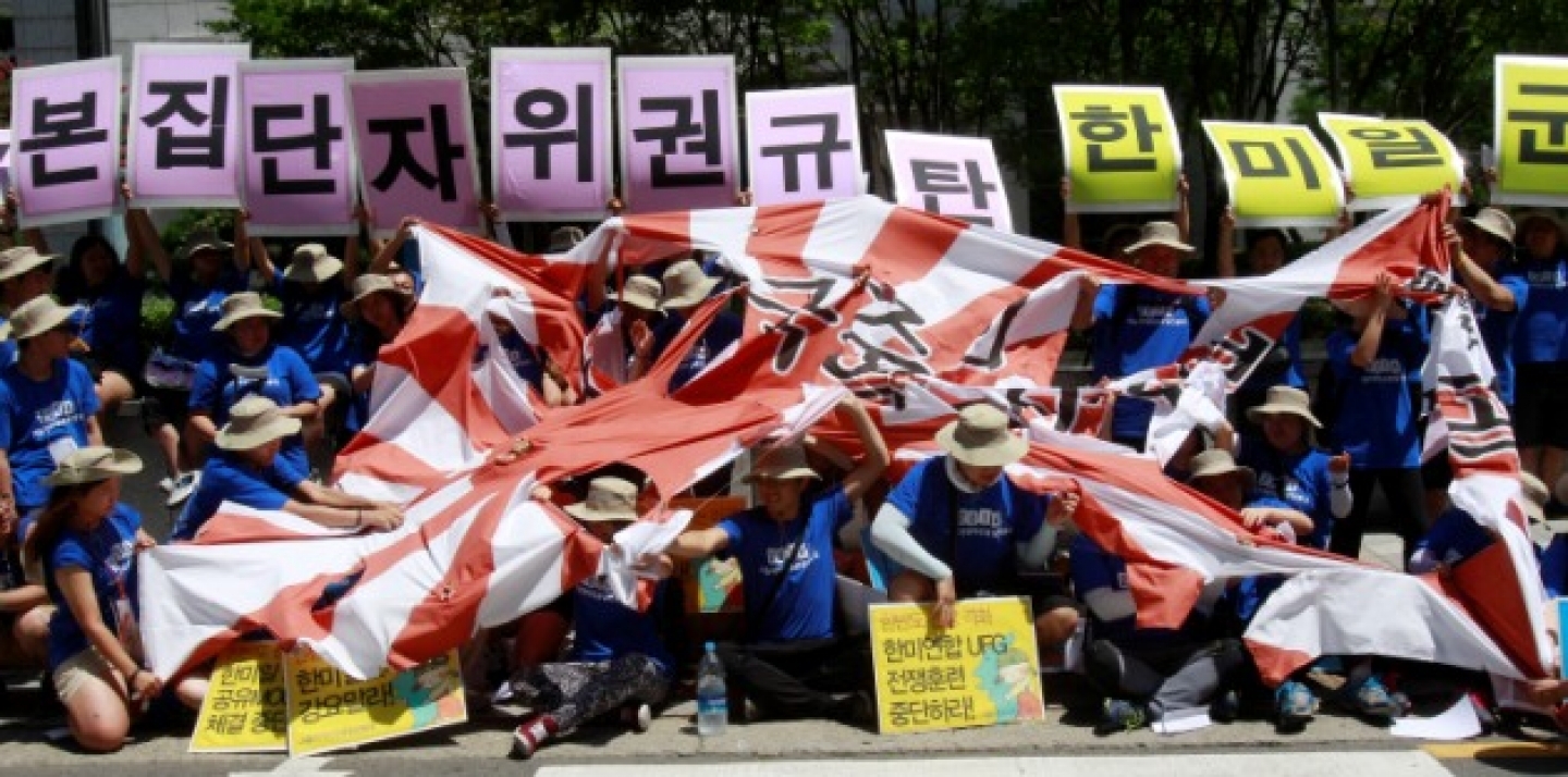 Protesters tear a Japanese rising sun flag during a rally against the Japanese government, demanding not to move toward exercising the right to collective self-defense seen as a prelude to the revival of Japan's past militarism, near the Japanese Embassy in Seoul, South Korea, Friday, Aug. 8, 2014. The cards read "Oppose collective self-defense plan." (AP Photo/Ahn Young-joon)