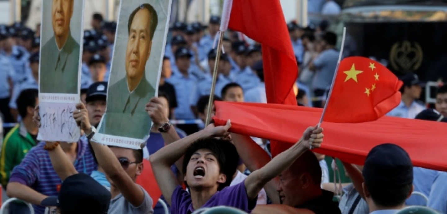 A Chinese man shouts anti-Japan slogans with Chinese national flags near portraits of the late Communist leader Mao Zedong in front of the Japanese Embassy in Beijing, September 2012. (AP Photo/Ng Han Guan)