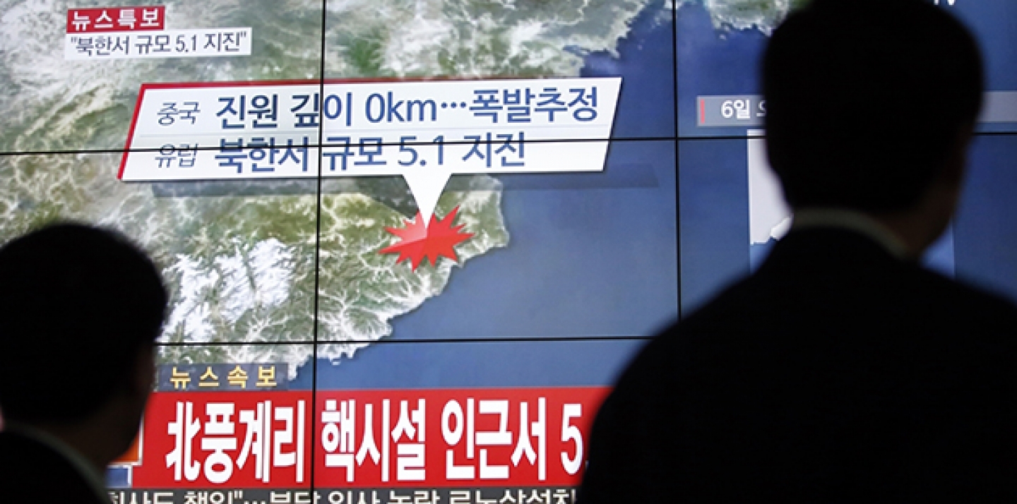 People walk by a screen showing the news reporting about an earthquake near North Korea's nuclear facility, in Seoul, South Korea, January 6, 2016. (AP Photo/Lee Jin-man)
