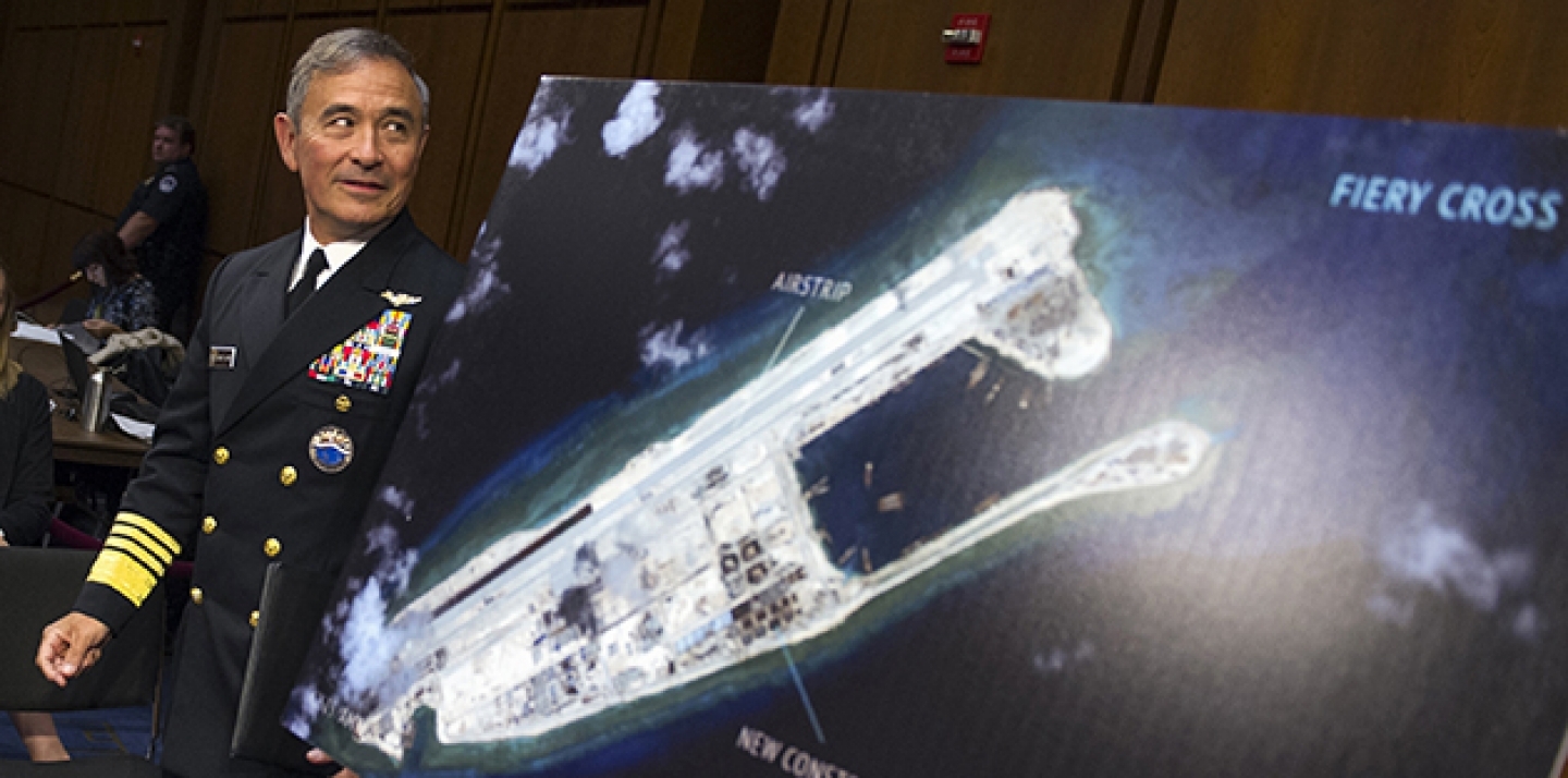 In this Sept. 17, 2015, file photo, Adm. Harry B. Harris, Jr., commander of US Pacific Command, walks past a photograph showing an island that China is building on the Fiery Cross Reef in the South China Sea, as he prepares to testify on Capitol Hill in Washington before the Senate Armed Services Committee hearing on maritime security strategy in the Asia-Pacific region. (AP Photo/Cliff Owen)