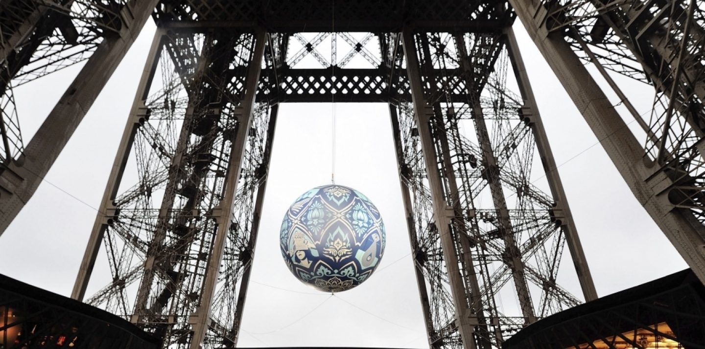 American street artist Shepard Fairey, aka Obey's piece 'Earth Crisis', a giant sphere themed on environment hangs between the first and second floor of the Eiffel Tower in Paris on Nov. 20, 2015. The piece was on display leading up to the 2015 climate change conference. (AP Photo/Binta Epelly)