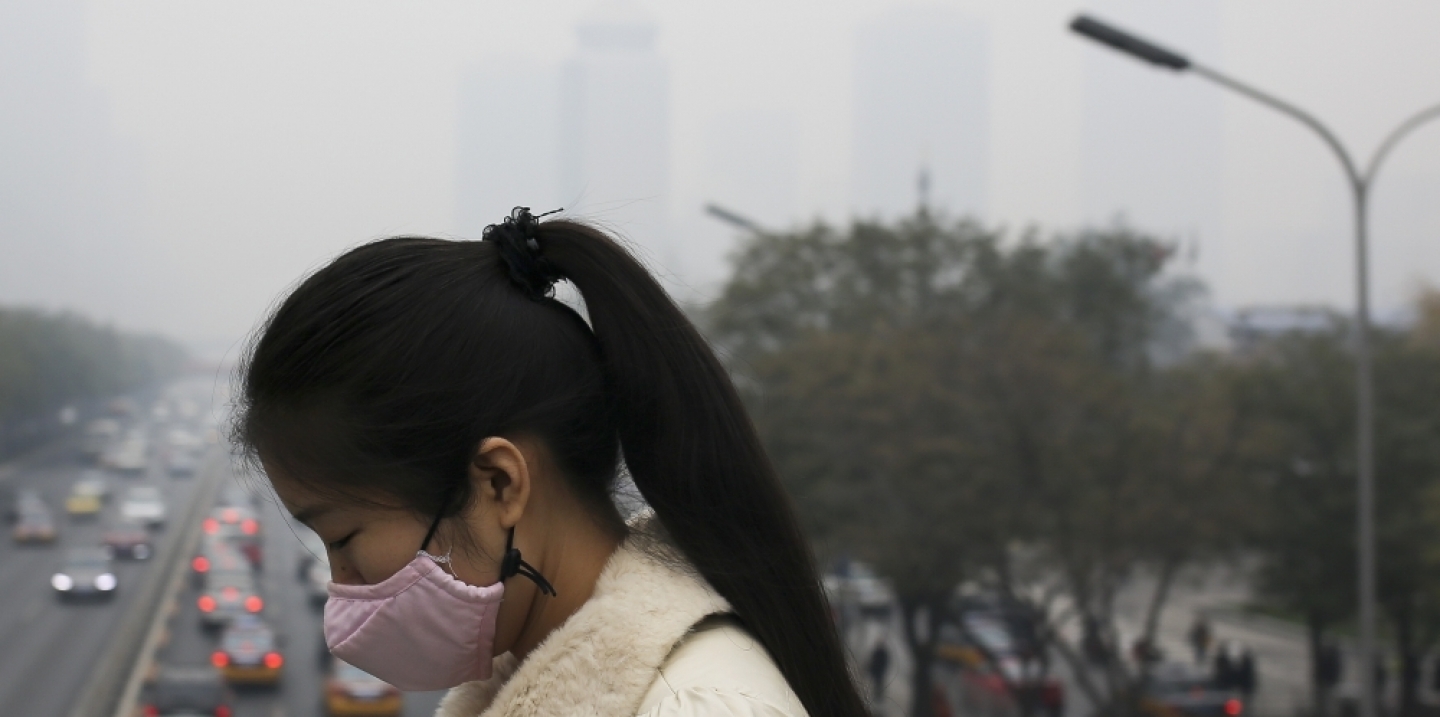 A woman wears a mask to protect herself from pollutants on a hazy day in Beijing. At the G20, the U.S. and China jointly confirmed the ratification of the Paris Agreement. (AP Photo/Andy Wong)