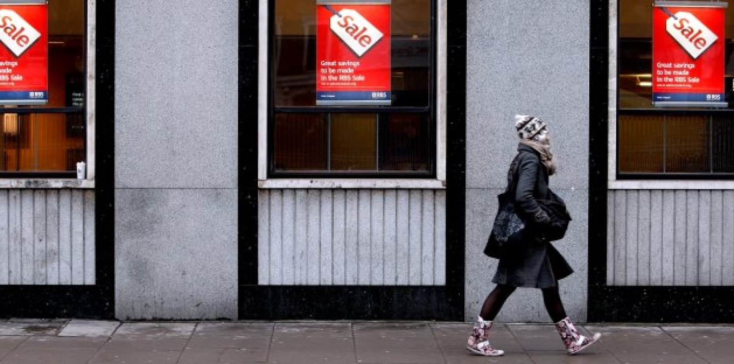 A woman passes a bank advertising a sale on its products, behind Oxford Street in London. (AP Photo/Kirsty Wigglesworth)
