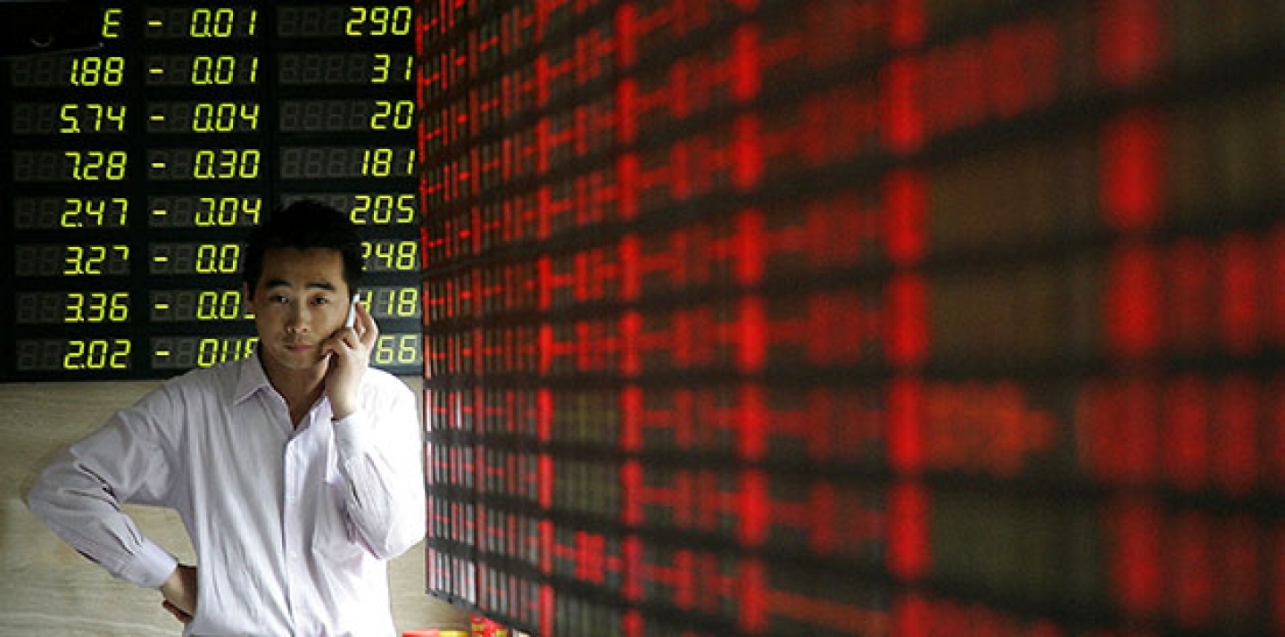 An investor talks on his mobile phone in front of the stock price monitor at a private securities company in Shanghai, China. (AP Photo)