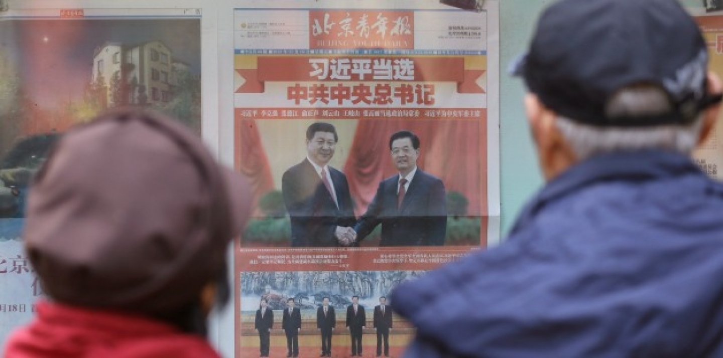 A Chinese couple look at a newspaper carrying photos of new General Secretary of the Communist Party of China Xi Jinping, top left, shaking hands with his predecessor Hu Jintao, top right, and Xi and other members of the party leadership in Beijing, China (AP Photo/Lee Jin-man).