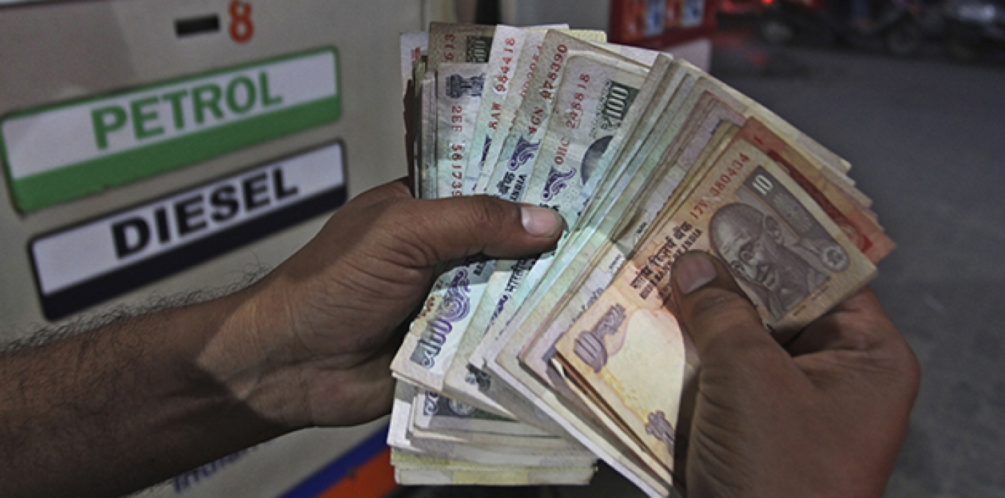 An employee of a fuel station counts Indian currency Rupees to give change to a customer after filling diesel in his car in Ahmadabad, India. (AP Photo/Ajit Solanki)