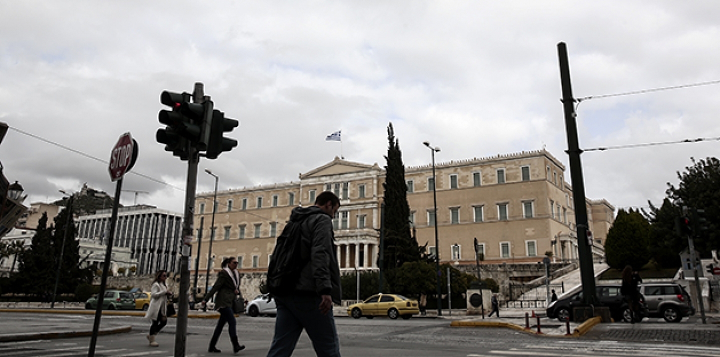People make their way in front of the parliament in Athens, Monday, Feb. 23, 2015. Greece will present a list of proposed reforms to debt inspectors on Monday to get final approval for an extension to its rescue loans. (AP Photo/Yorgos Karahalis)