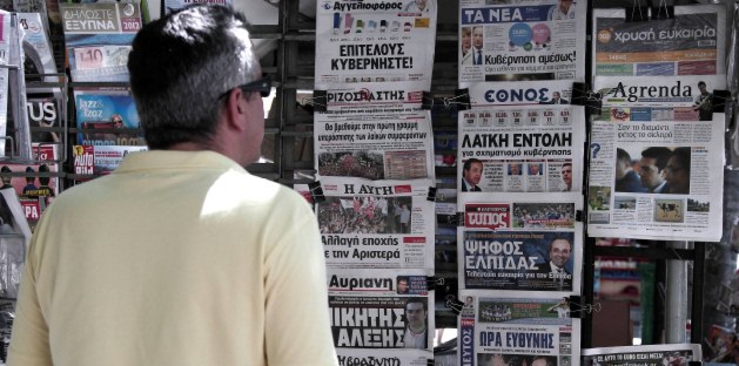 A man reads newspaper headlines displayed at a kiosk following the election of the pro-bailout New Democracy party in the Greek national election. (AP Photo/Dimitri Messinis)