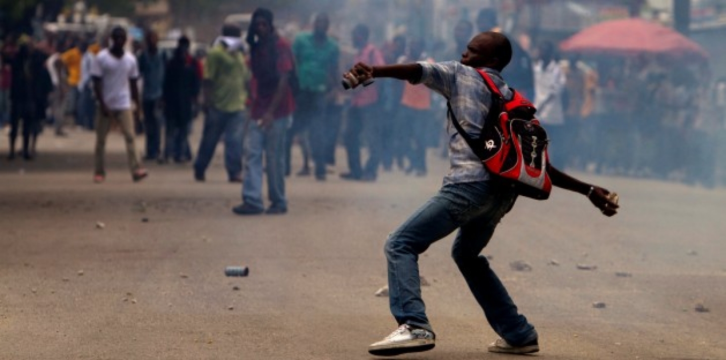 Amidst tear gas, a man throws stones against police officers during a protest in Port-au-Prince, Haiti, Sept. 14, 2011. (AP Photo/Dieu Nalio Chery)