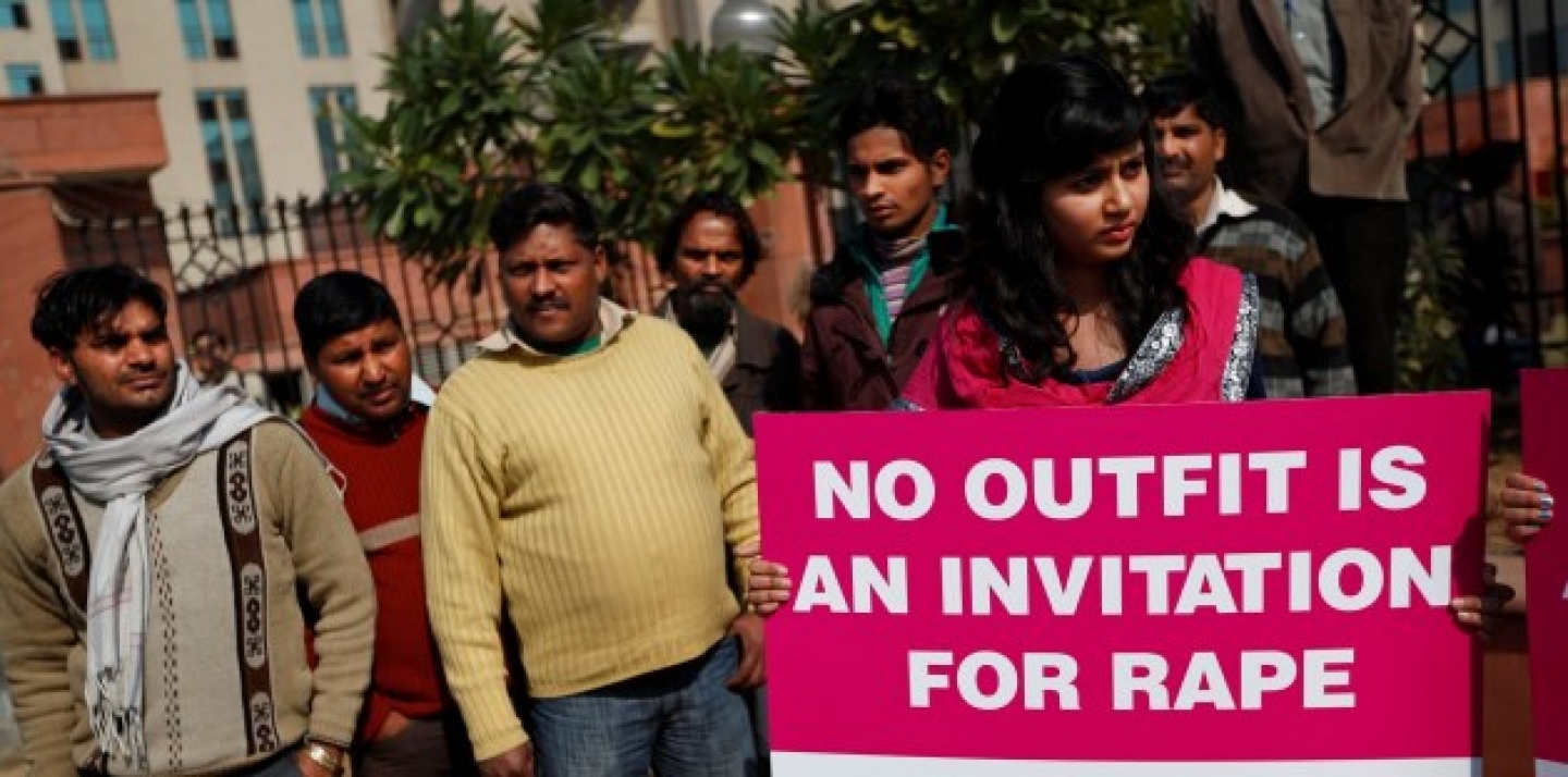 Indian men watch as a woman protests outside the court where the accused in a gang rape of a 23-year-old woman are to be tried, in New Delhi, India. (AP Photo/Saurabh Das)
