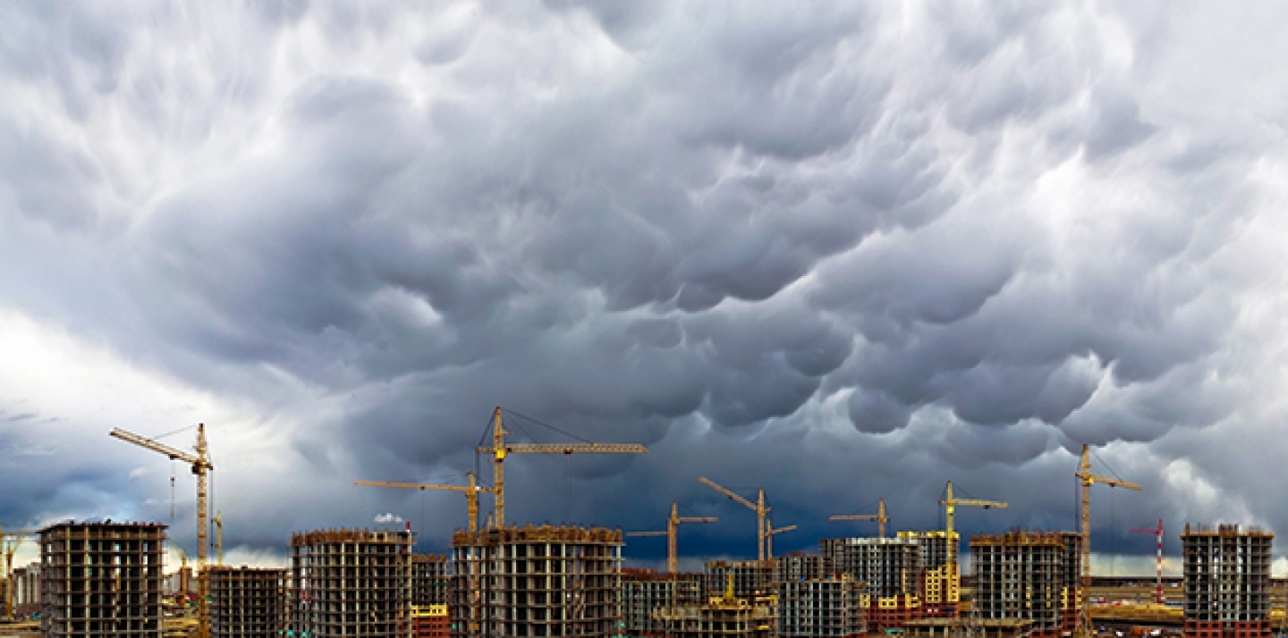 Construction cranes appear along a stormy skyline. (Shutterstock)