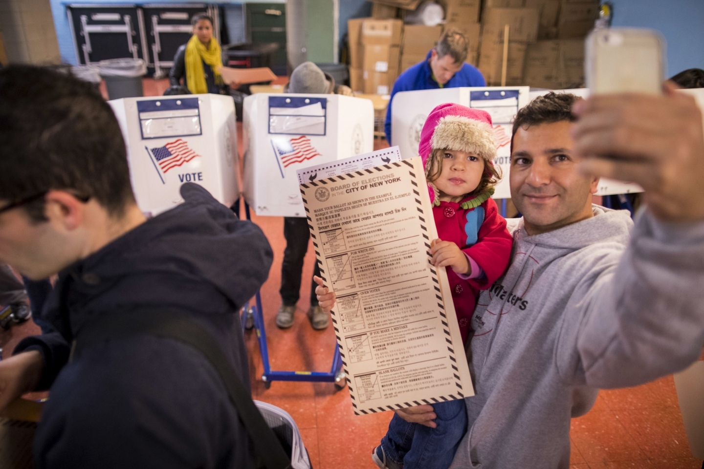 A man takes a selfie with his child as he waits to vote at a polling station in Brooklyn borough of New York on Tuesday, Nov. 8, 2016. (AP Photo/Alexander F. Yuan)