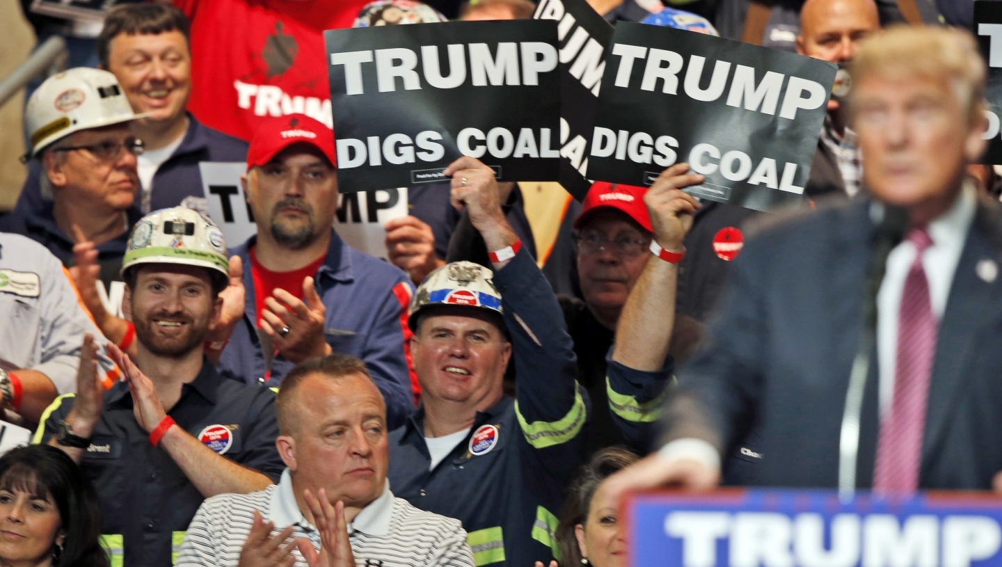 Coal miners wave signs as Republican presidential candidate Donald Trump speaks during a rally in Charleston, W.Va. in May 2016. (AP Photo/Steve Helber, File)