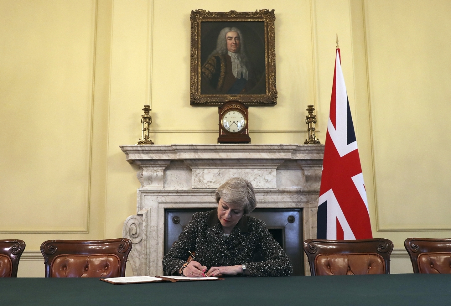 Britain's Prime Minister Theresa May, sitting below a painting of Britain's first Prime Minister Robert Walpole, signs the official letter to European Council President Donald Tusk, in 10 Downing Street, London, Tuesday March 28, 2017, invoking Article 50 of the bloc's key treaty, the formal start of exit negotiations. (Pool Photo via AP/Christopher Furlong)