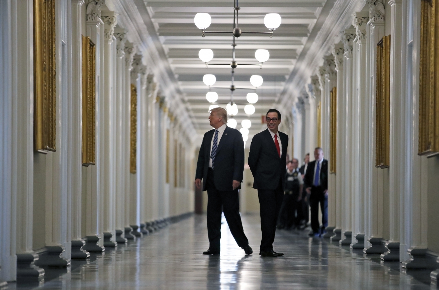 President Donald Trump walks with Treasury Secretary Steve Mnuchin as they look at portraits of the previous secretaries of the Treasury. (AP Photo/Alex Brandon)