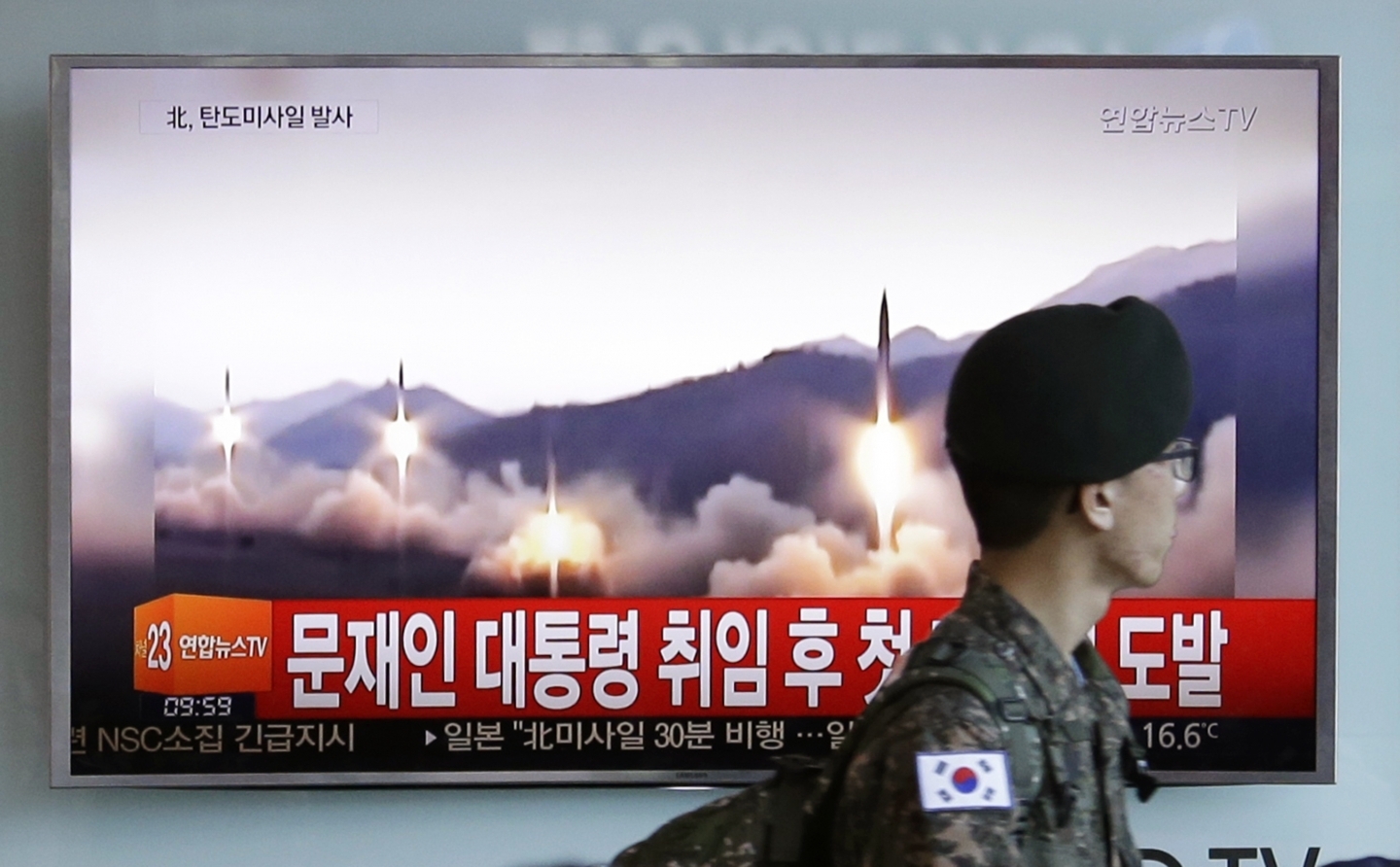 A South Korean soldier walks by a TV screen showing missiles being test-launched by North Korea (AP Photo/Ahn Young-joon)