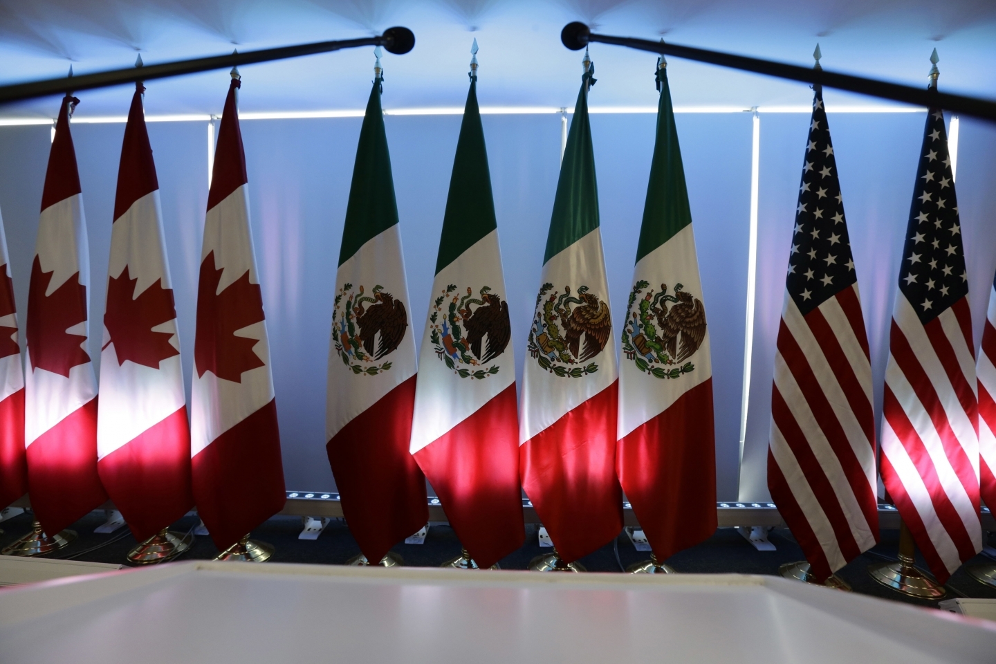 National flags representing Canada, Mexico, and the US are lit by stage lights at the NAFTA renegotiations in Mexico City, Tuesday, Sept. 5, 2017. (AP Photo/Marco Ugarte)