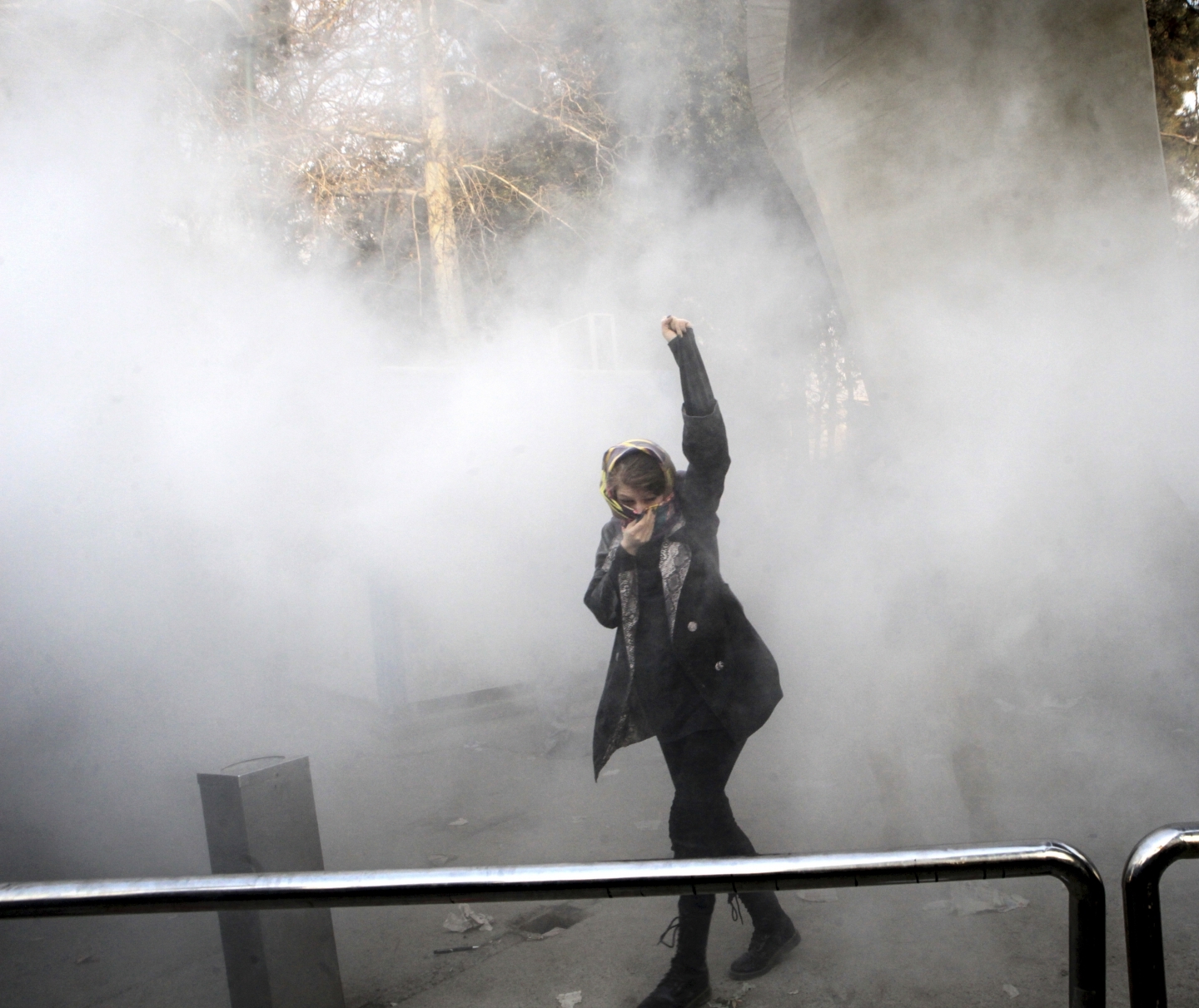 A protestor runs from a smoke grenade thrown by anti riot police during a December 30 rally against the Iranian government. (AP Photo)