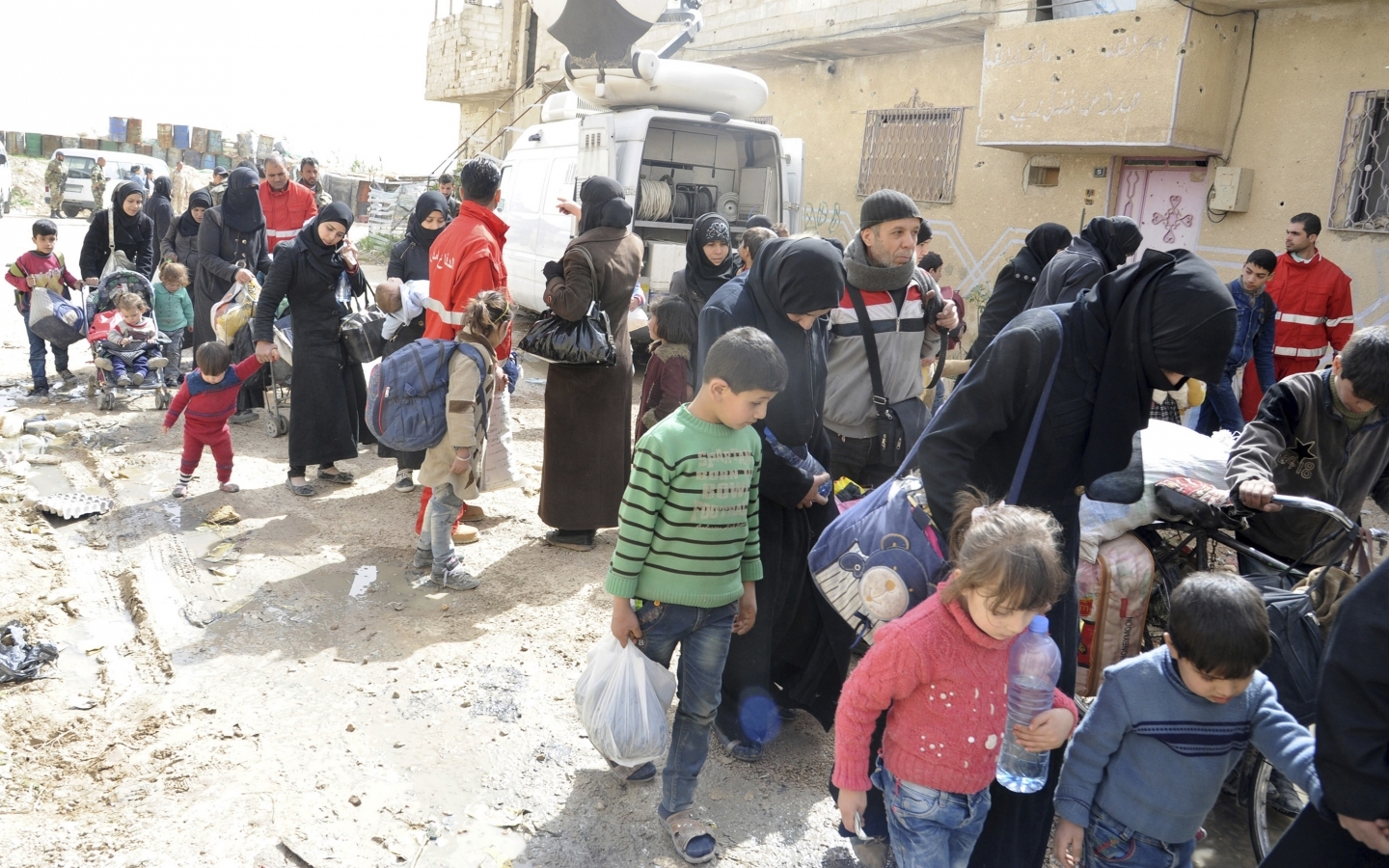 Civilians carry their belongings as they leave Douma, Syria, on March 24, 2018. The area experienced chemical attacks on April 8. (SANA via AP)