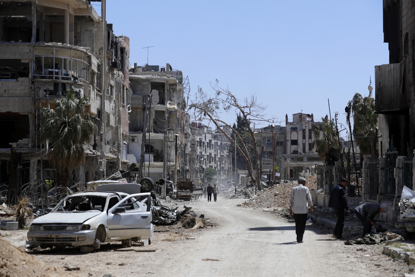 Syrians walk through destruction in the town of Douma, the site of a chemical weapons attack on Monday, April 16, 2018. (AP Photo/Hassan Ammar)