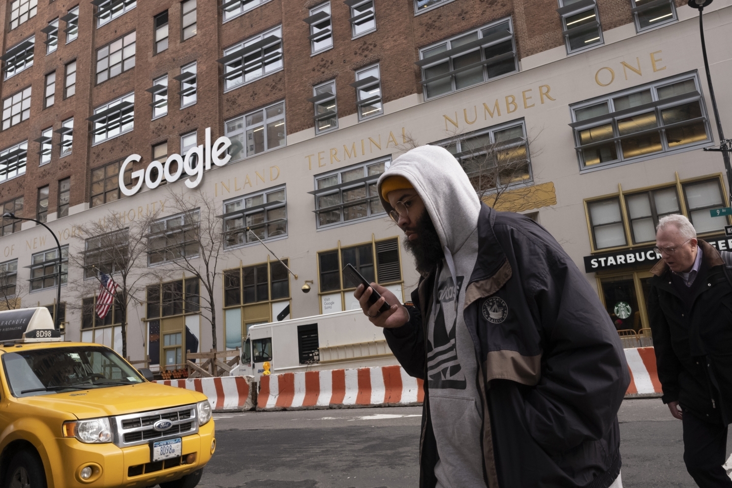 A man using a mobile phone walks past Google offices in New York. (AP Photo/Mark Lennihan)