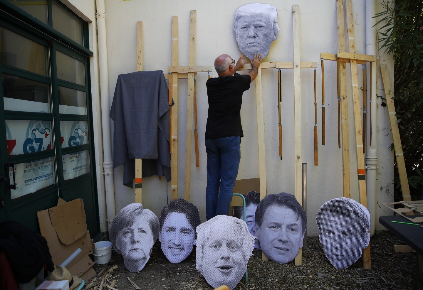 A man fixes an image of President Donald Trump to a wooden pole as he prepares for an anti-G7 demonstration at a camp near Hendaye, France. (AP Photo/Francois Mori)