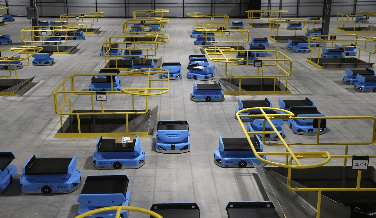 Dozens of Amazon robots transport packages from workers to chutes that are organized by zip code, at an Amazon warehouse facility in Goodyear, Arizona. (AP Photo/Ross D. Franklin)
