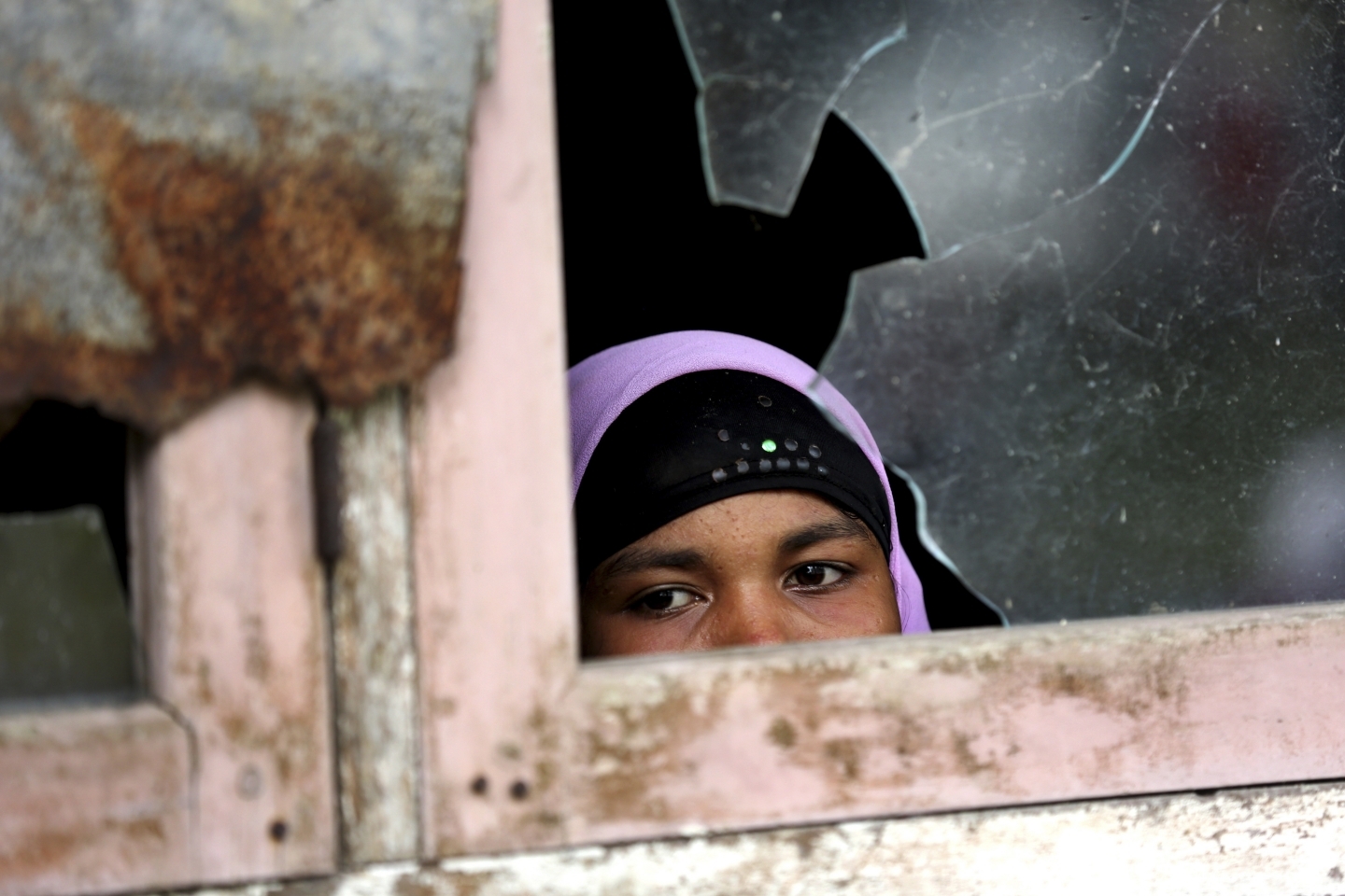 A woman peers out from a temporary shelter housing ethnic Rohingya displaced by internal conflict in Myanmar (AP Photo/Tatan Syuflana)
