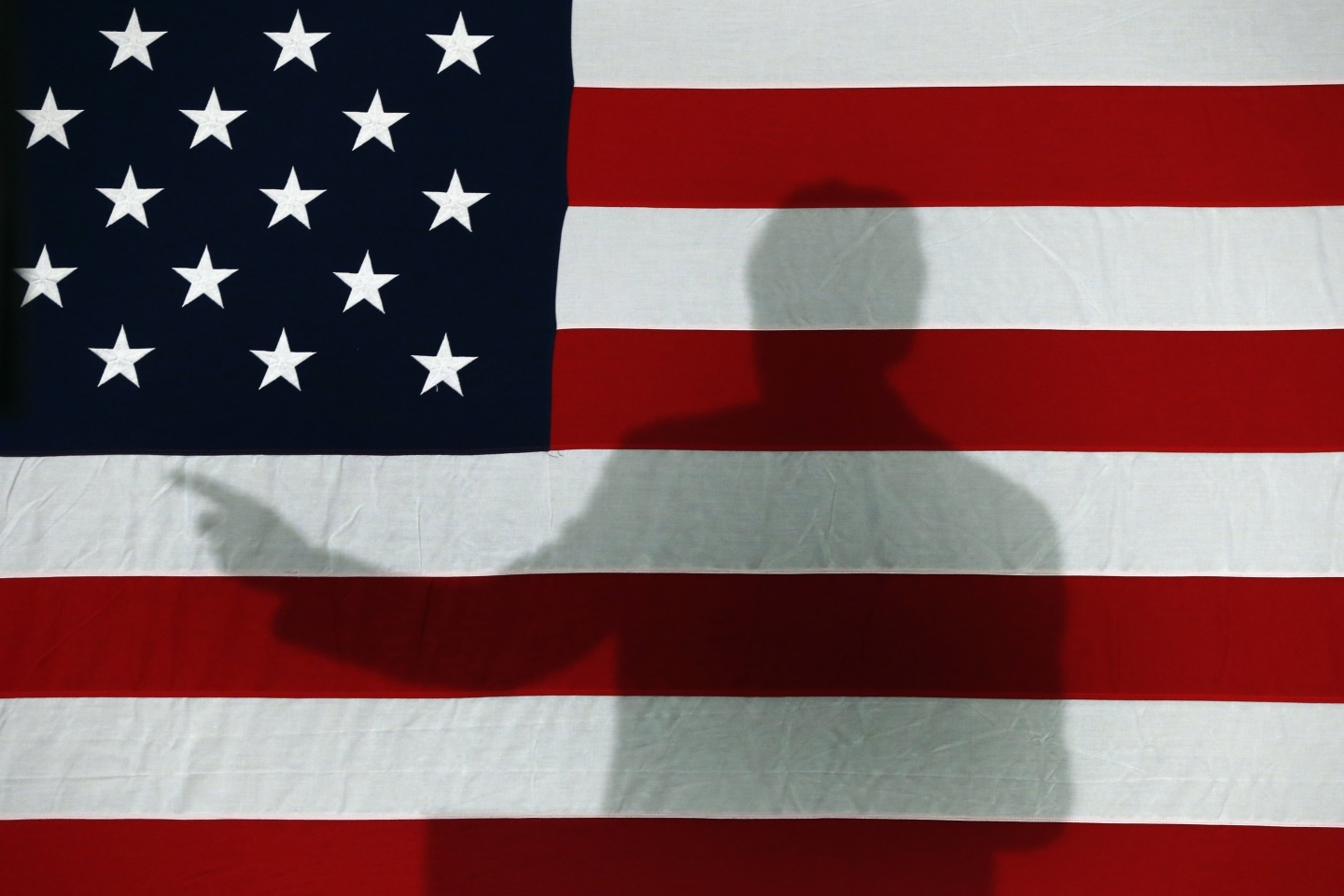 Former President Bill Clinton casts a shadow on an American flag during a 2016 campaign stop (AP Photo/Paul Sancya)