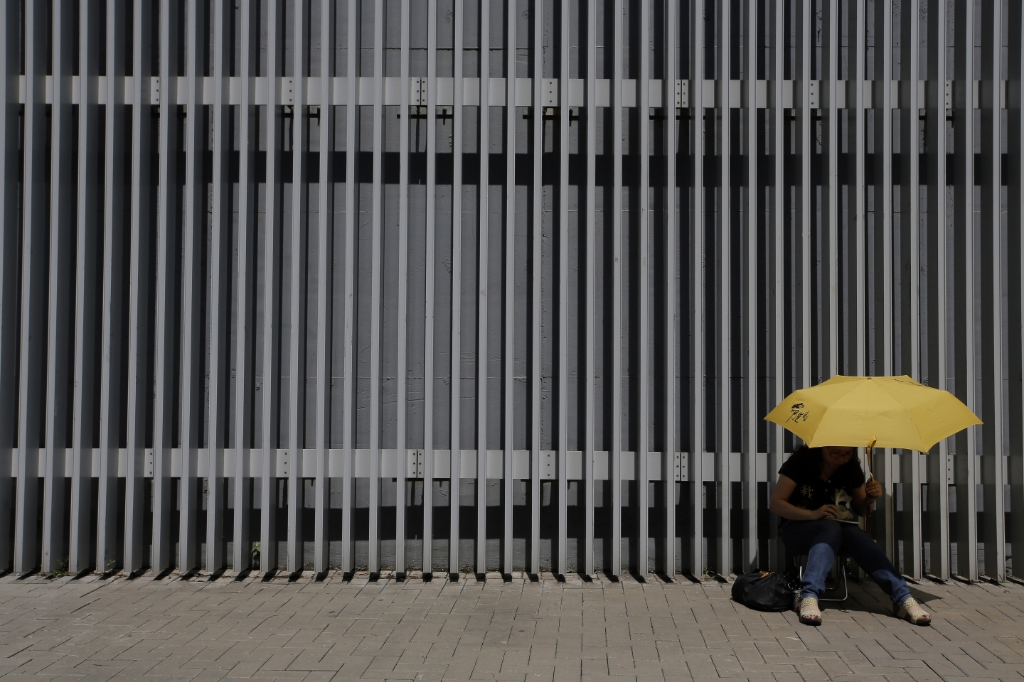 A pro-democracy protester sits with a yellow umbrella outside government headquarters in Hong Kong (AP Photo/Vincent Yu)
