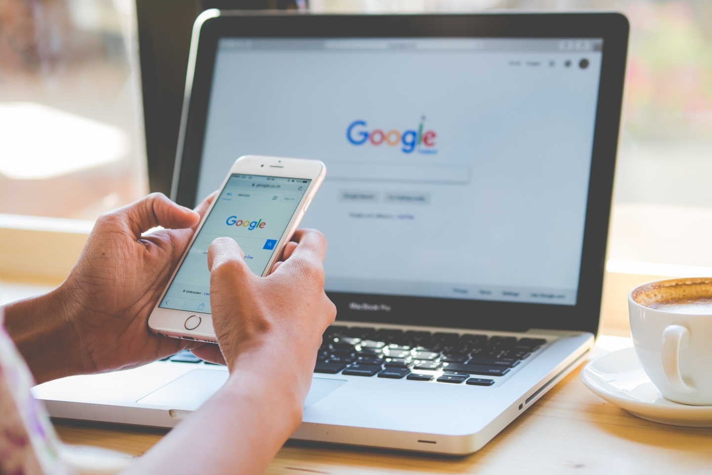 A woman is typing on Google search engine from a laptop and smart phone. (Shutterstock)