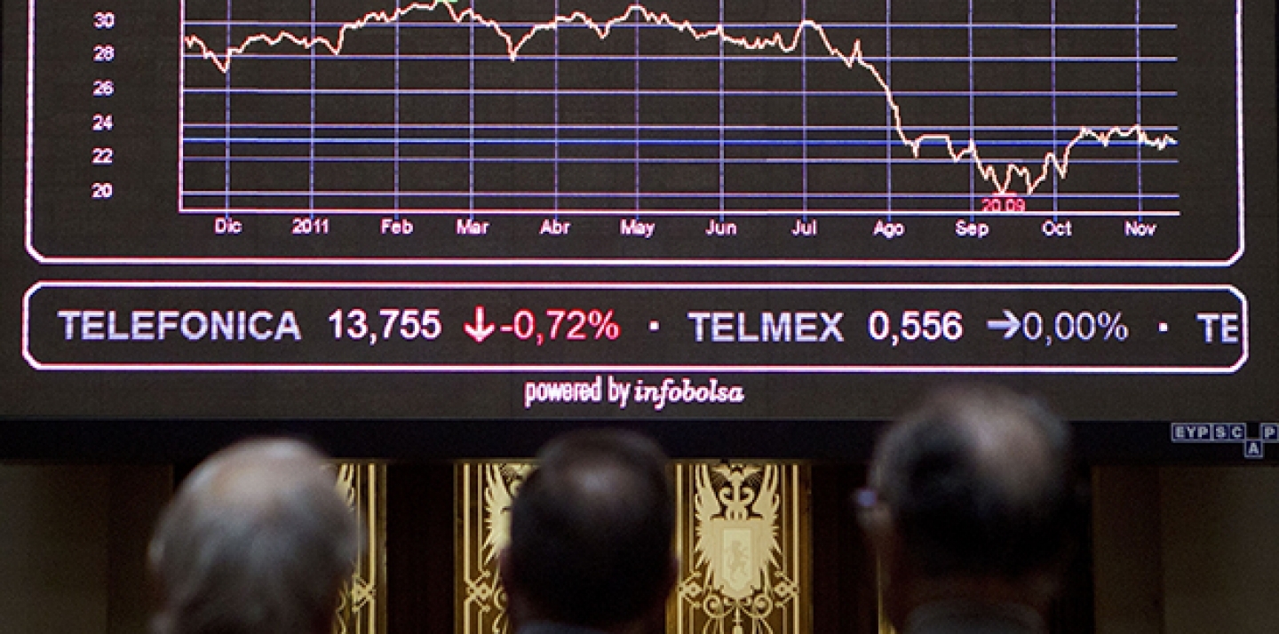 Brokers look at the main screen at the Stock Exchange in Madrid. (AP Photo/Paul White)