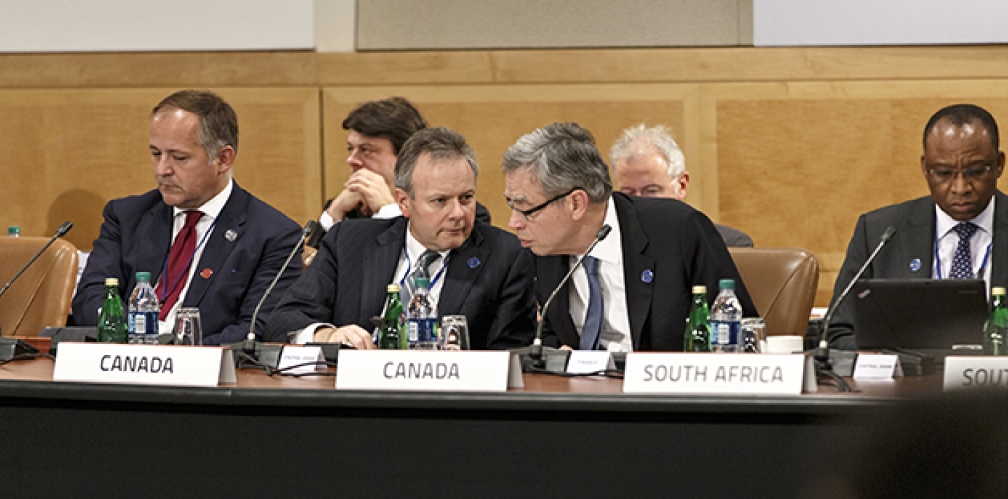 Canada's Minister of Finance Joe Oliver, center right, leans in to speak with Stephen Poloz, governor of the Bank of Canada, center left, as the Group of Twenty nations gather at the International Monetary Fund and World Bank meetings in Washington. (AP Photo/J. Scott Applewhite)