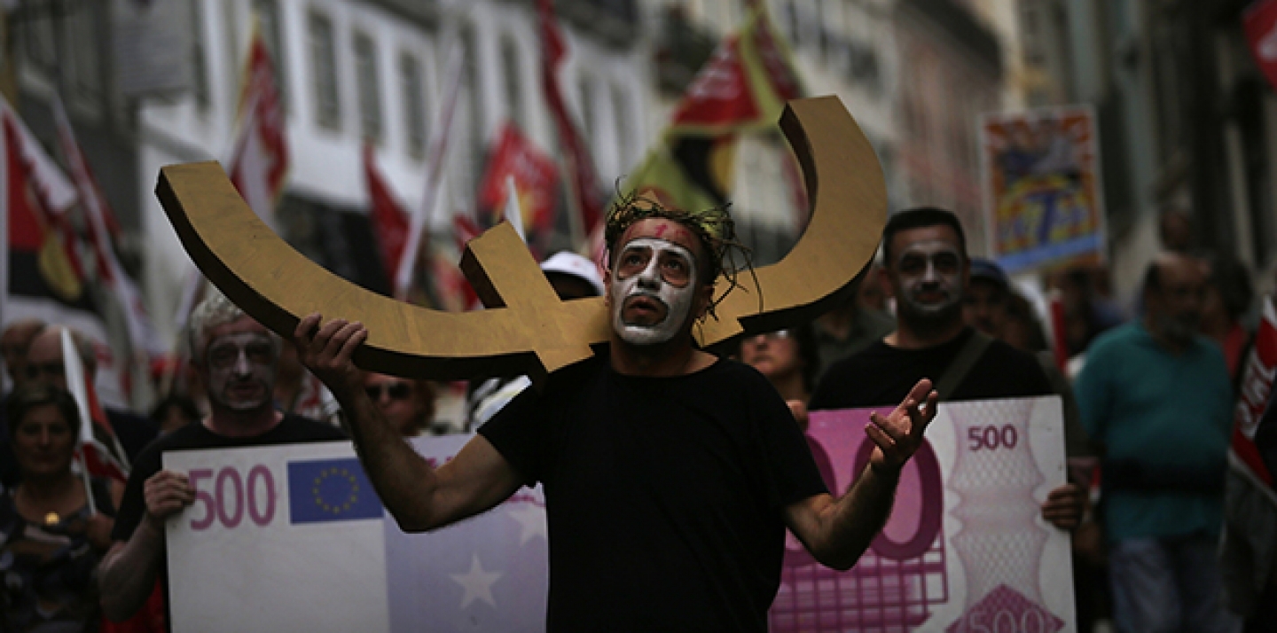 A man carries a euro currency symbol on his shoulder as he marches with others towards the parliament during a protest against austerity measures in Portugal. (AP Photo/Francisco Seco)